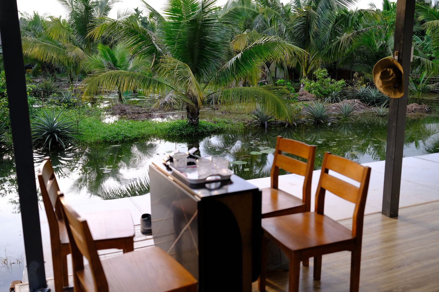Bàn ghế trên hiên sàn nhựa vân gỗ nhìn ra vườn dừa